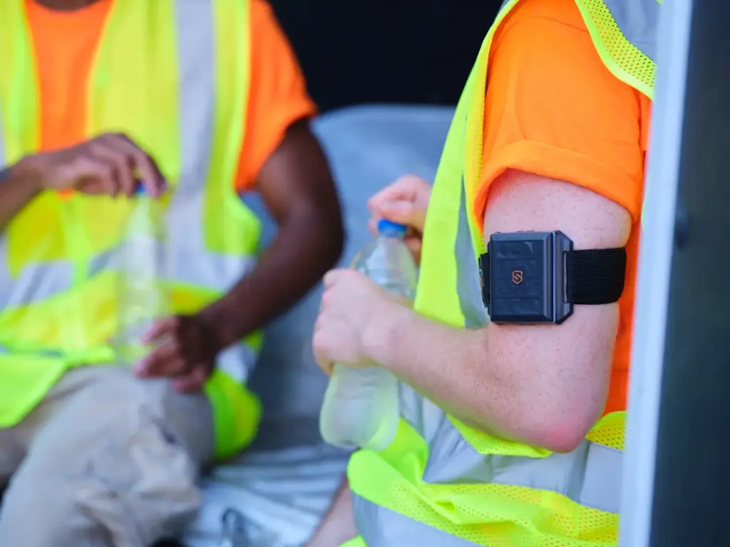closeup of 2 workers resting, both with a SlateSafety BAND V2 on their arms. 